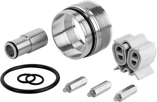Verchromte Metallteile, einschließlich einer runden Buchse, O-Ringen, einem Stecker und zwei Bolzen, arrangiert auf neutralem Hintergrund. Ideal Standard ist die Marke.